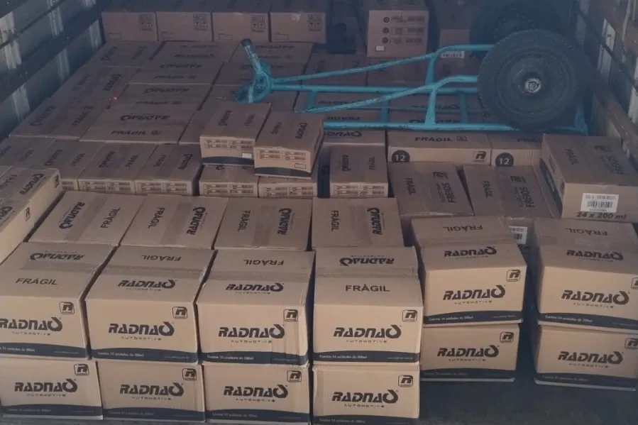 Carga acomodada no baú, com o carrinho de transporte pronto para a descarga